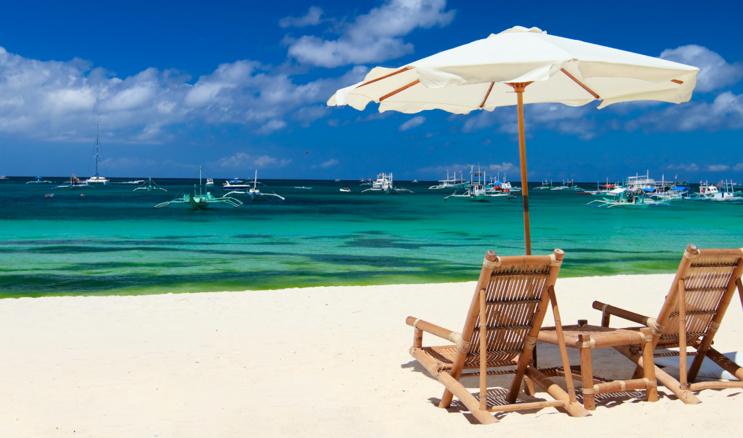 Two empty chairs on a beach under an umbrella in nice weather